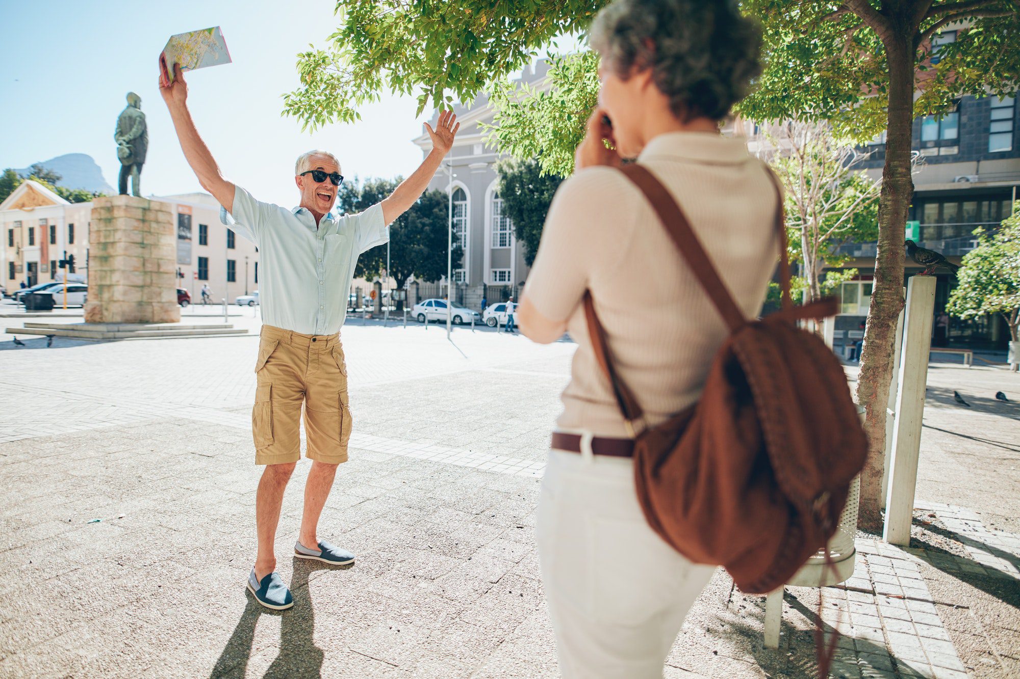 Woman taking a photo of a man who is excited about medicare premiums being at an all time low.