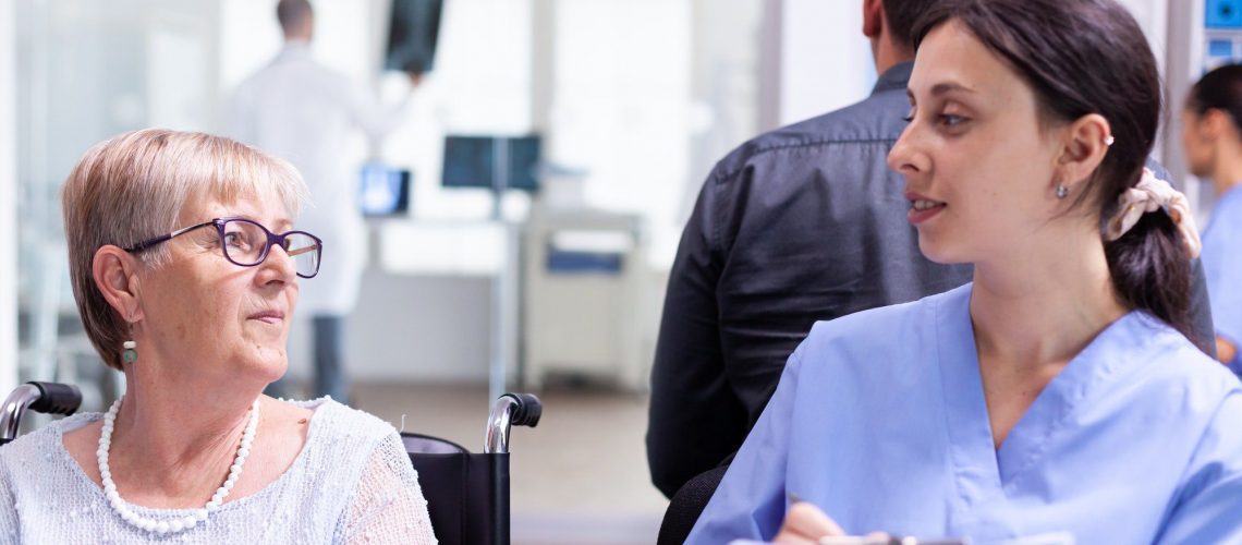Elderly woman discussing medicare with a nurse in a skilled nursing facility.